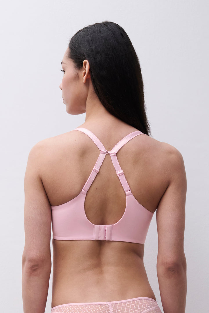 Woman wearing a pink bra against a plain background