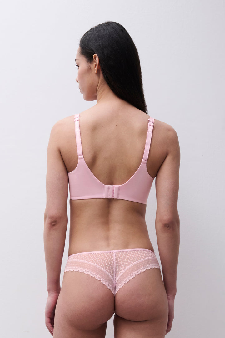 Woman wearing a pink bra and panties set against a plain background