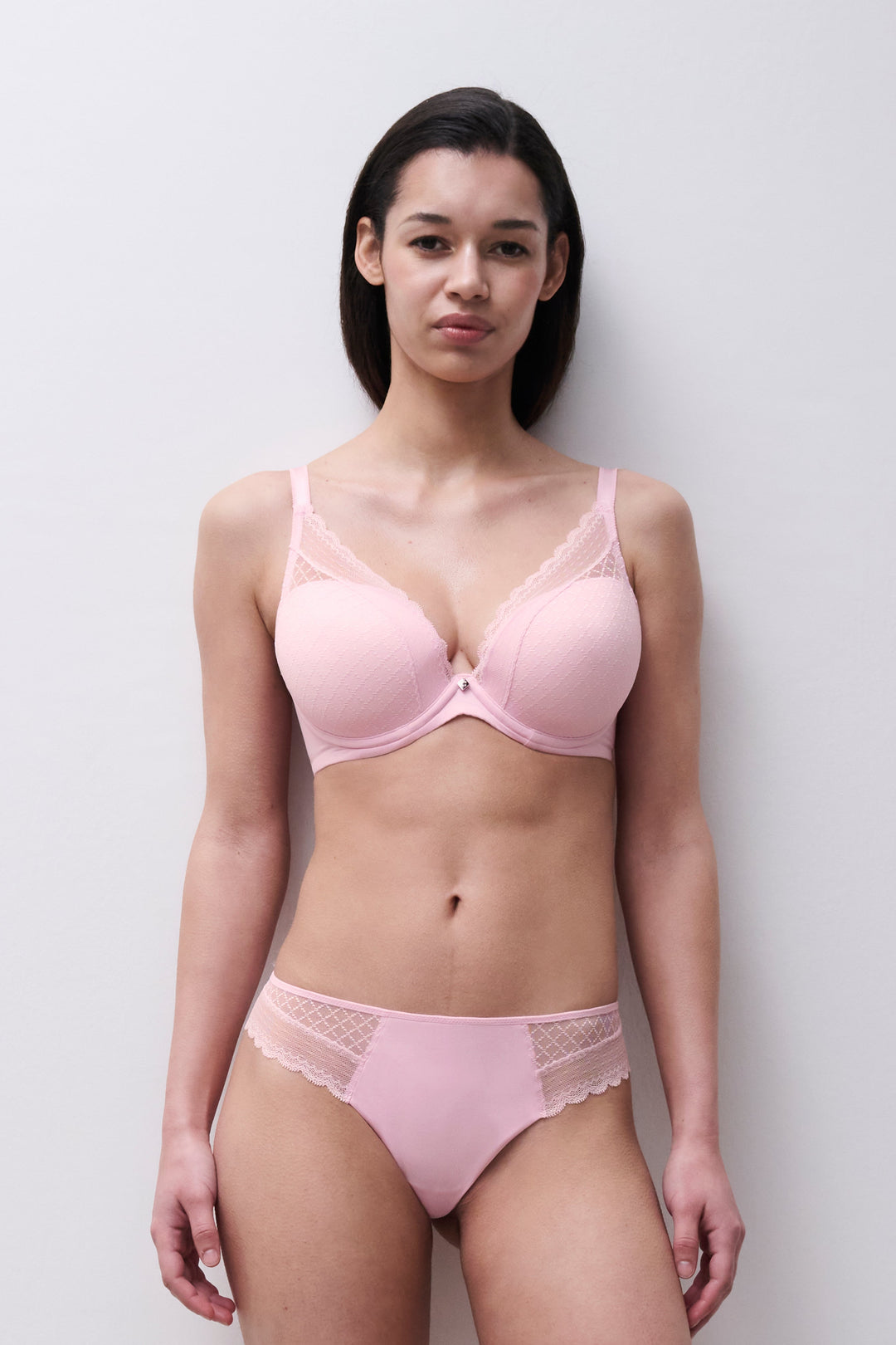 Woman wearing a pink bra and panties set against a plain background