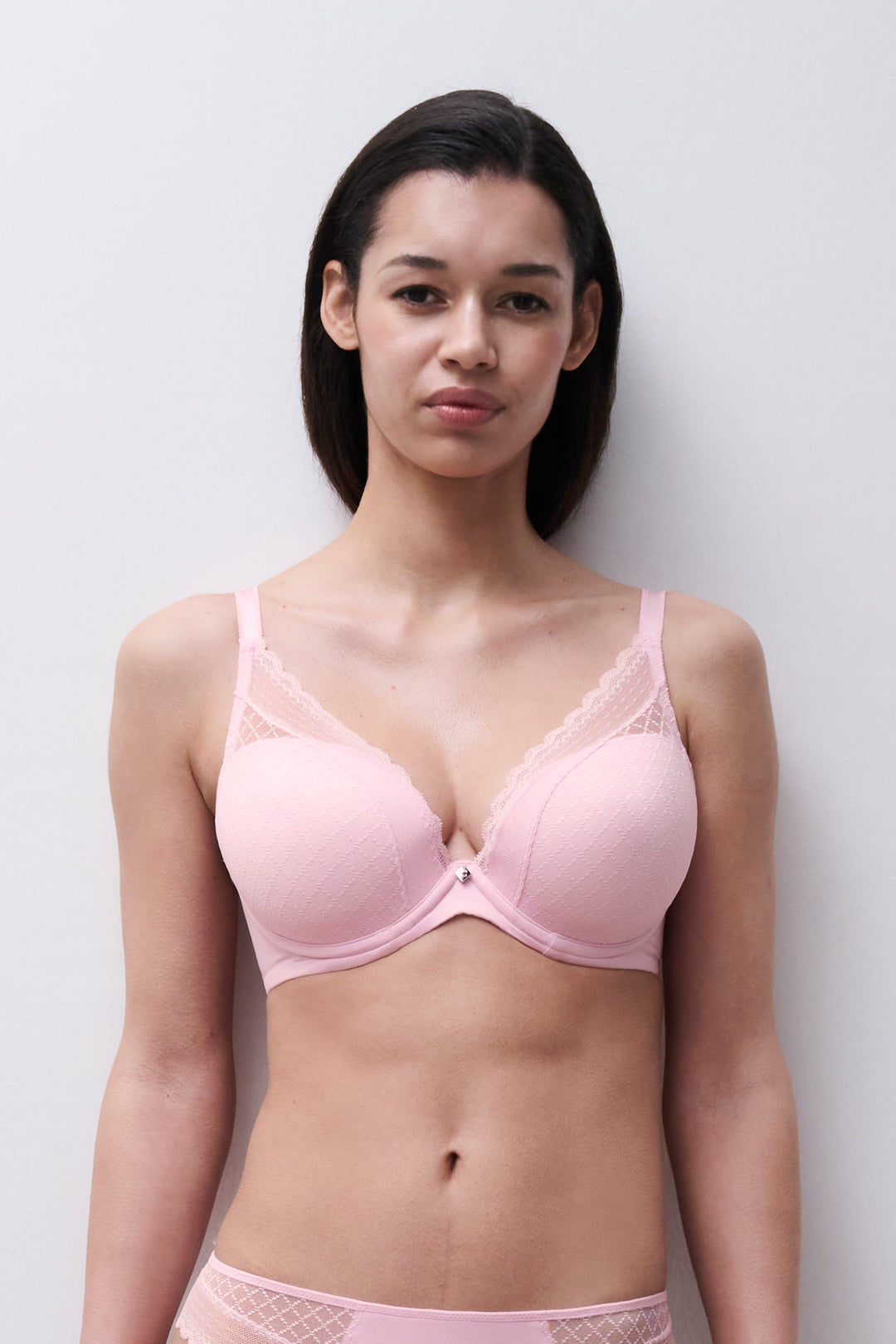 Woman wearing a pink bra and underwear set against a plain background