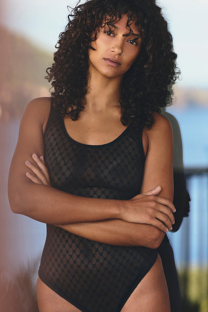 Woman wearing a black mesh swimsuit with blurred background