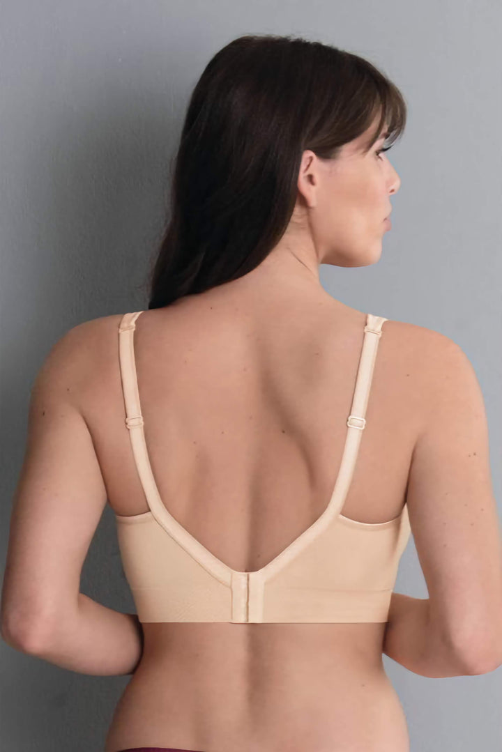 Woman wearing a beige bra against a gray background