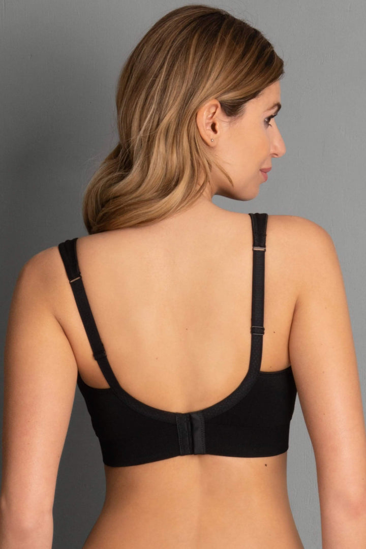 Woman wearing a black bra against a gray background