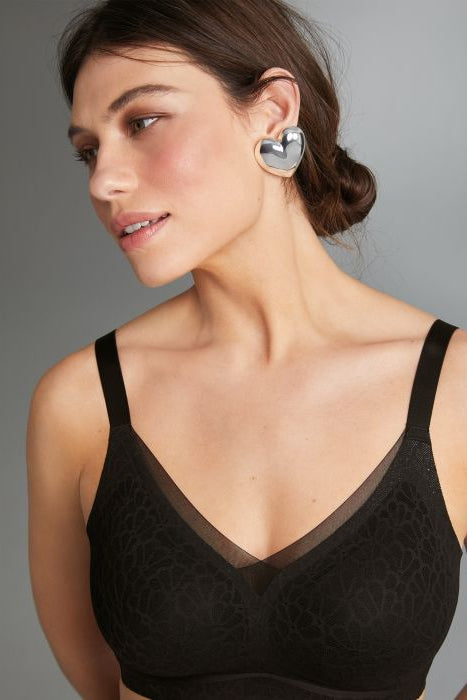 Woman wearing a black bralette against a gray background