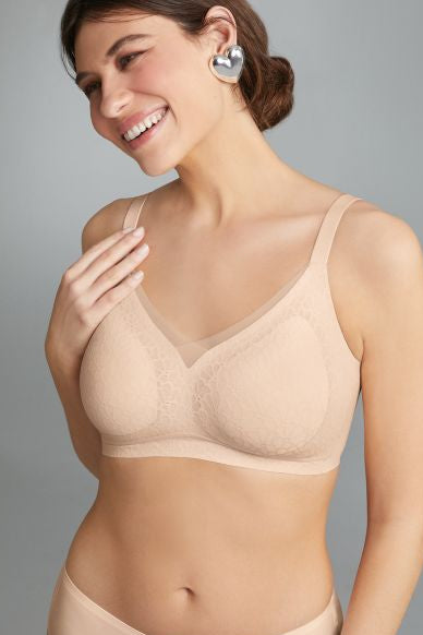 Woman wearing a beige bra and panties set against a gray background
