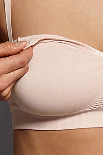 Beige strapless bra being adjusted on a person against a neutral background