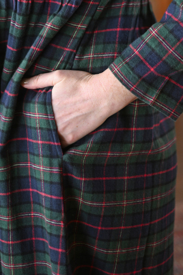 Close-up of a person wearing a plaid nightgown with a hand in the pocket.