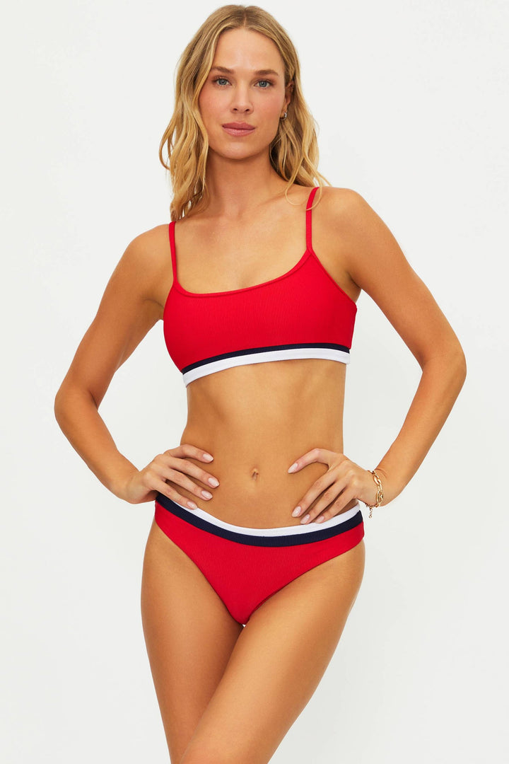 Woman wearing a red bikini with white and blue stripes on a light gray background
