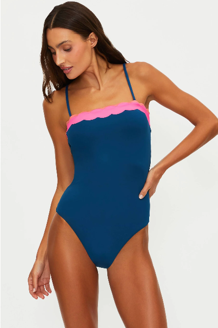 Woman wearing a blue one-piece swimsuit with pink trim on a white background