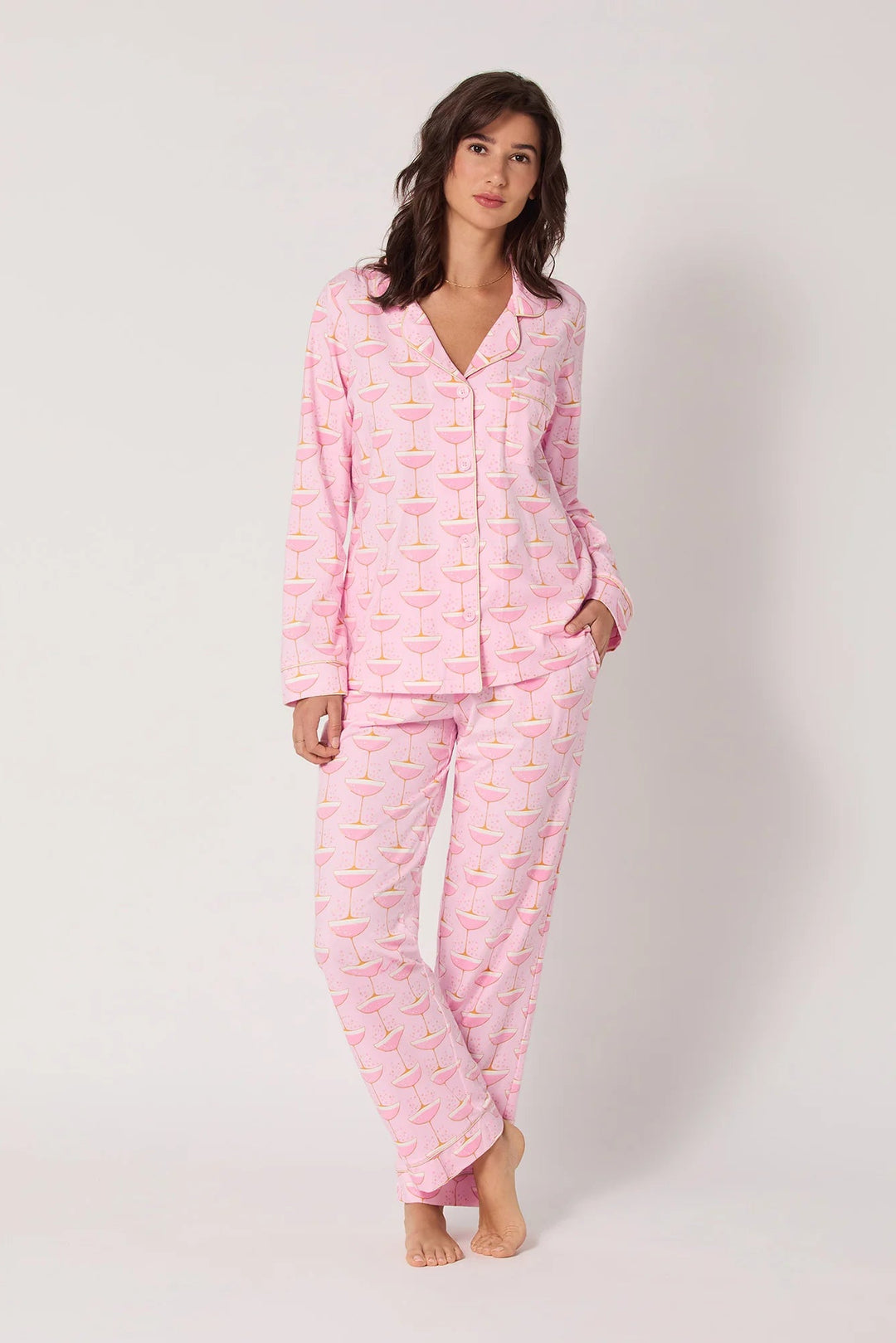 Woman wearing a pink champagne pajama set on a white background