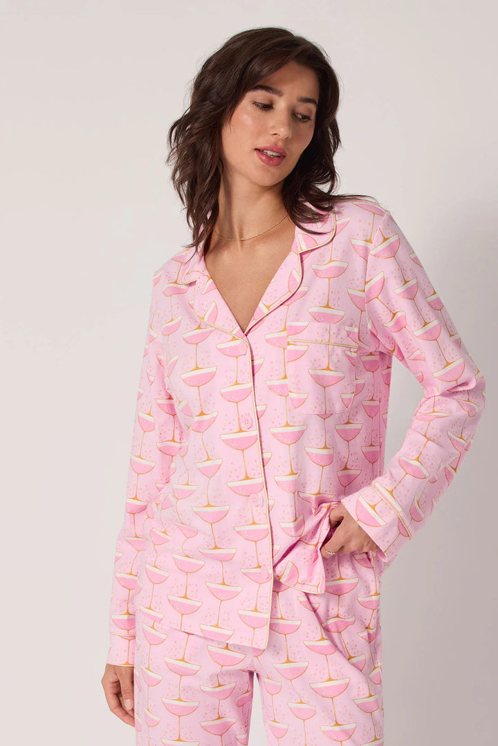 Woman wearing pink champagne print pajamas with a cocktail pattern on a plain background