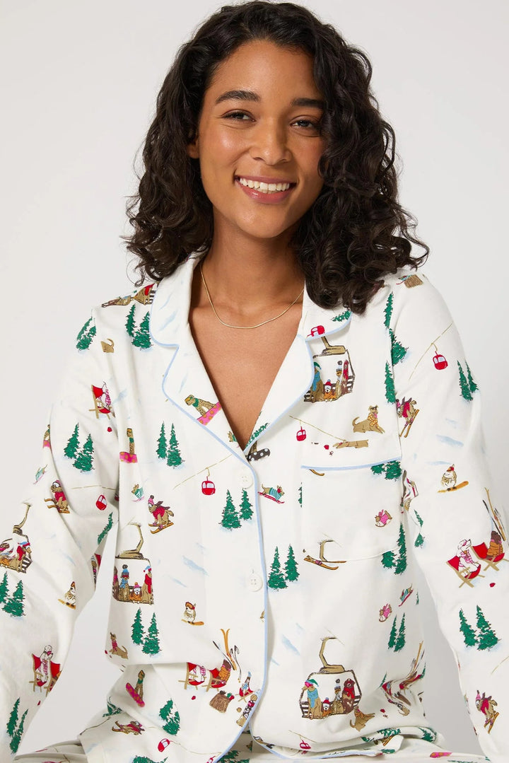 Woman wearing a white pajama top with Christmas-themed dog pattern on a plain background