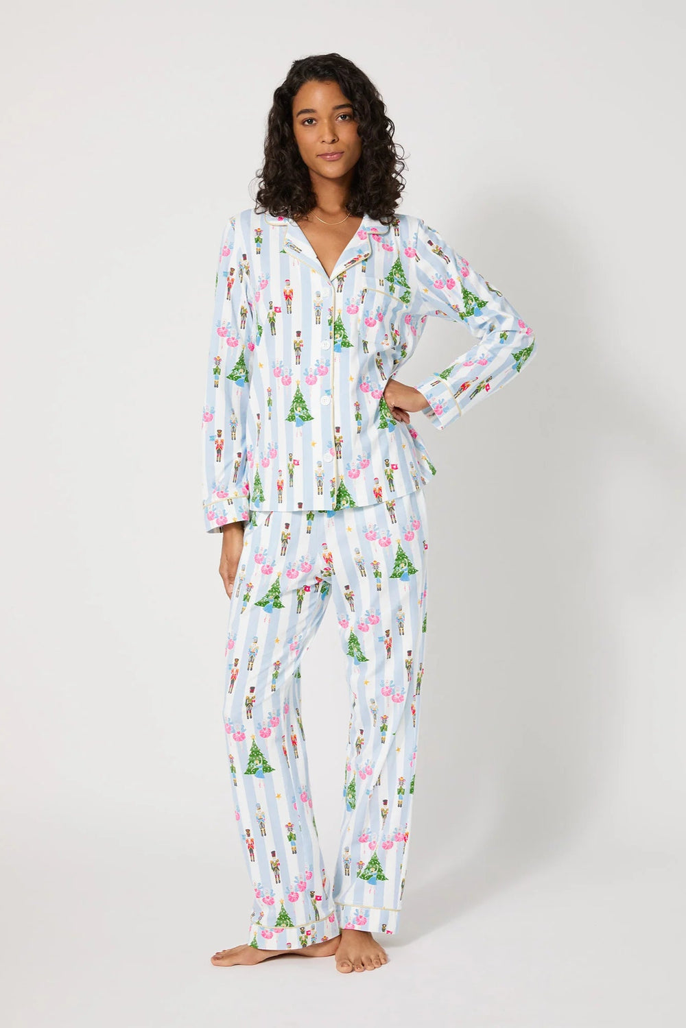 Woman wearing a festive pajama set with Christmas tree pattern on a white background