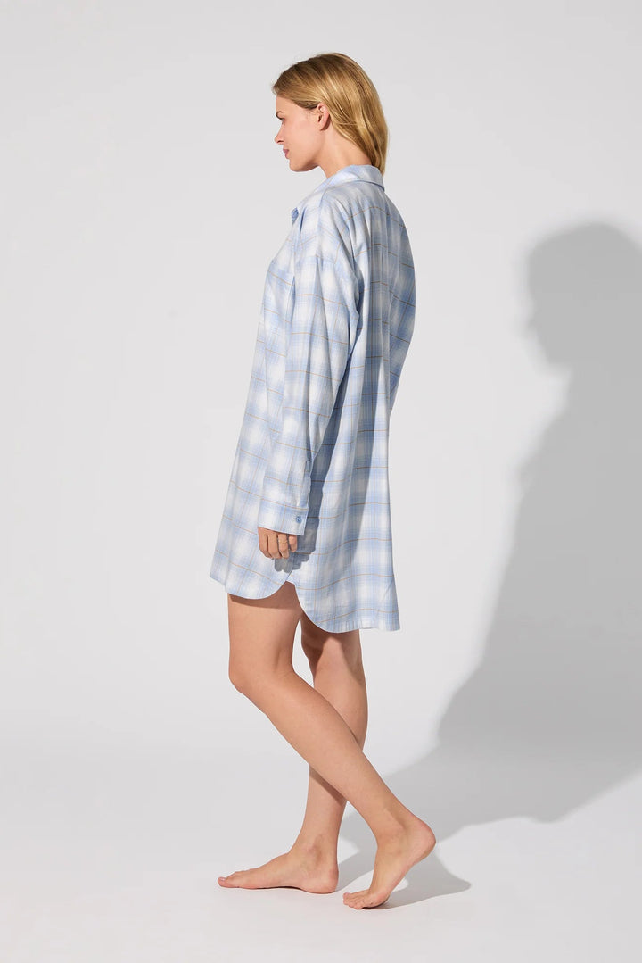 Woman wearing a light blue checkered nightshirt on a white background