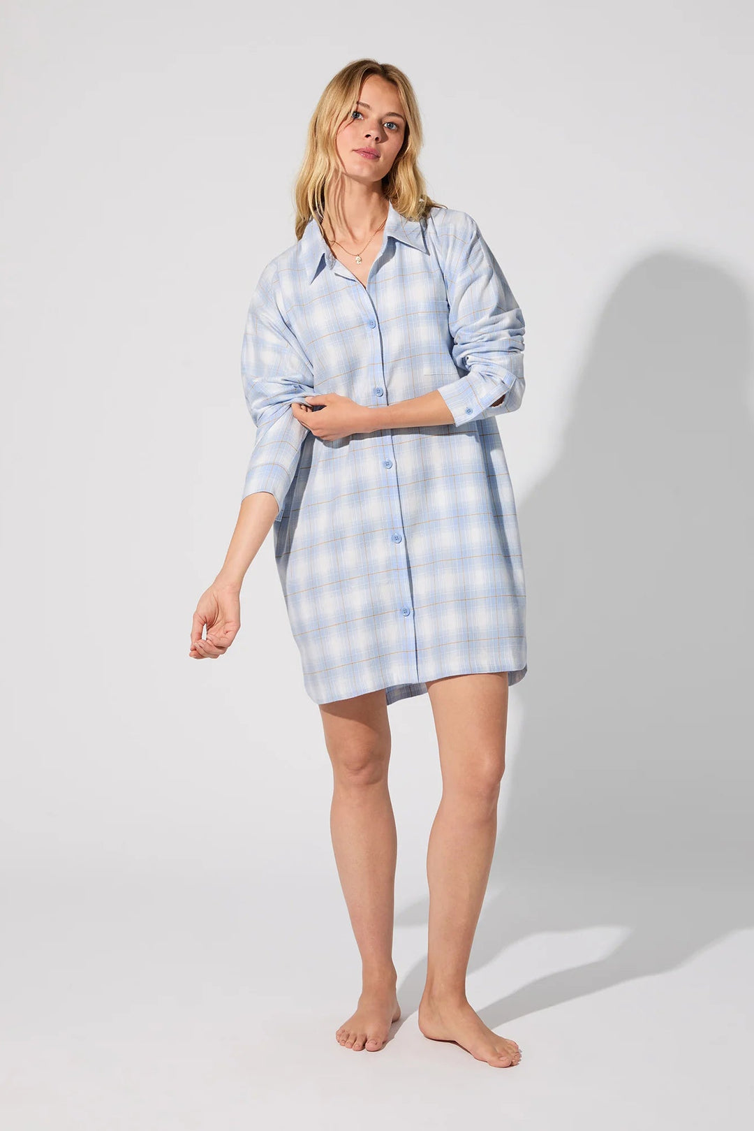 Woman wearing a light blue checkered dress against a white background