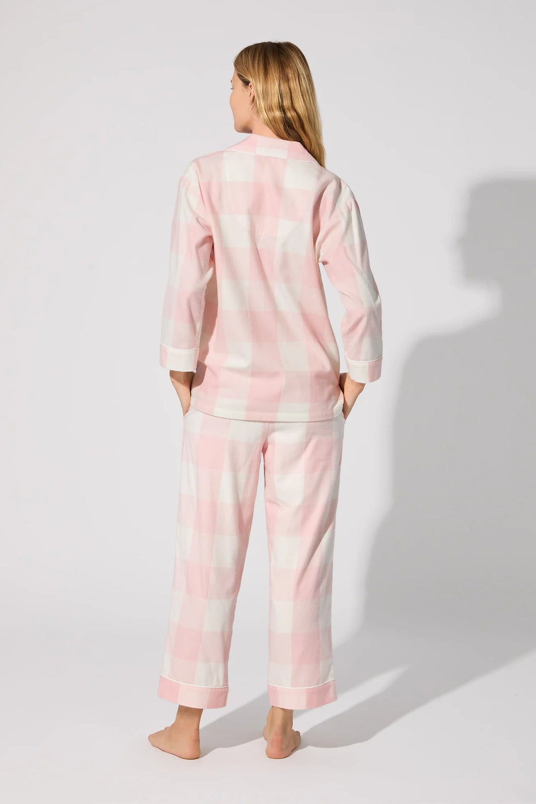 Person wearing a pink plaid pajama set on a white background
