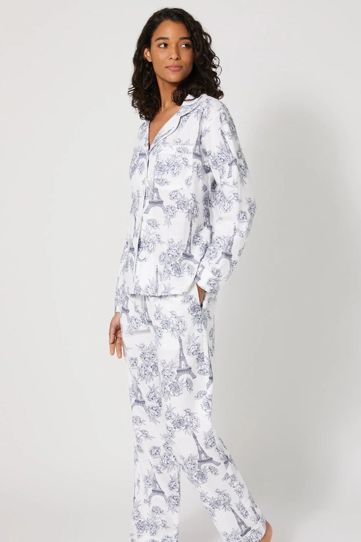 Woman wearing a white floral pajama set on a plain background