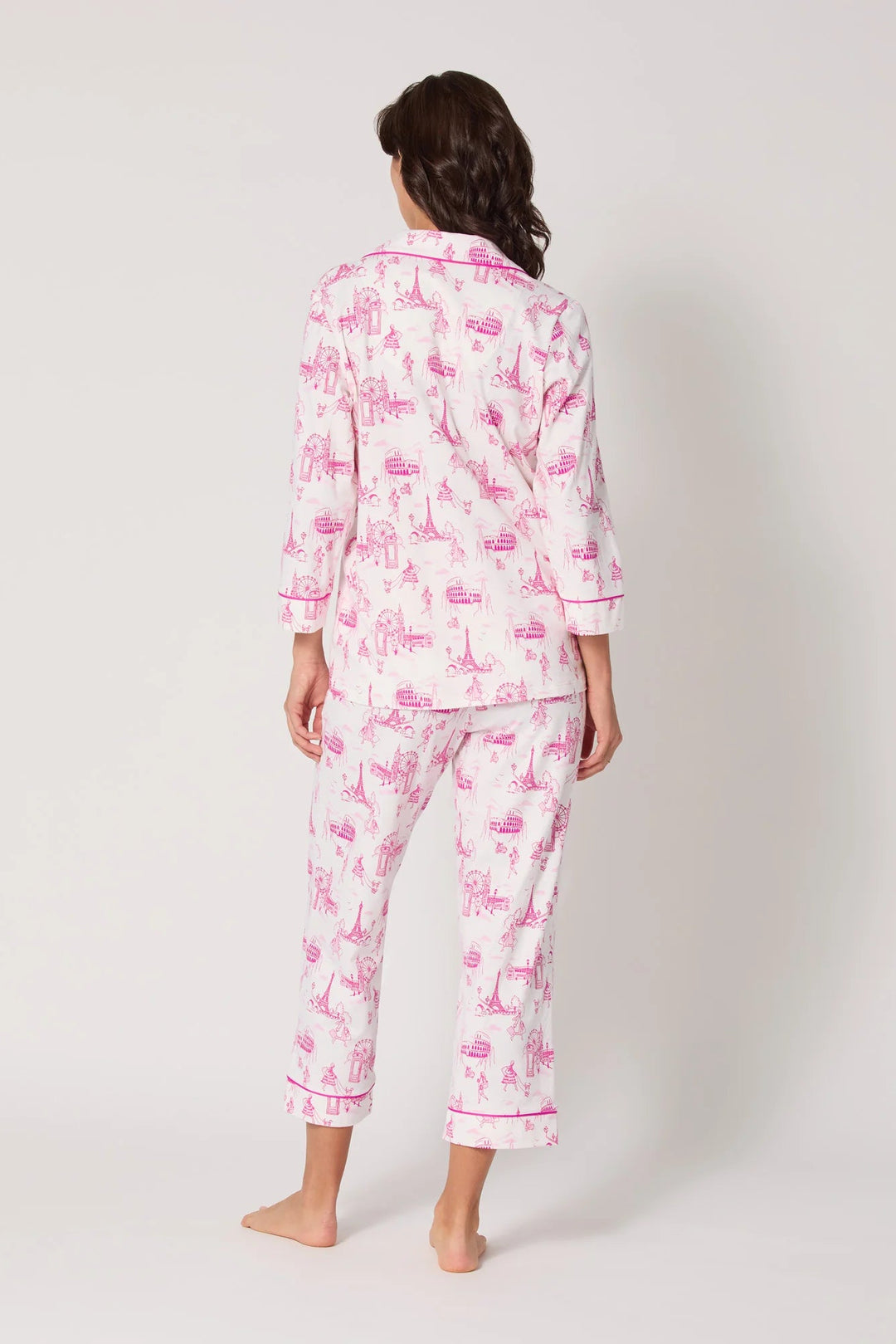 Woman wearing a pink and white patterned pajama set on a white background