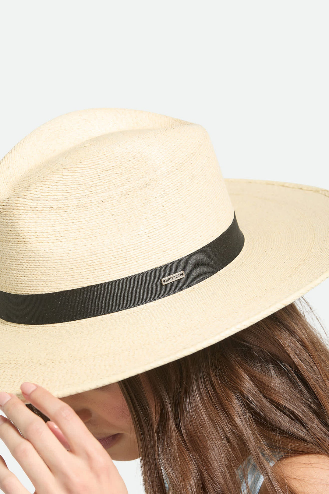 Beige straw hat with a black band on a light gray background