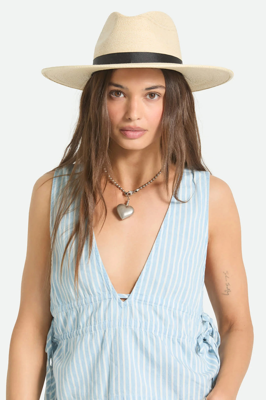 Woman wearing a straw hat and a light blue striped dress on a white background