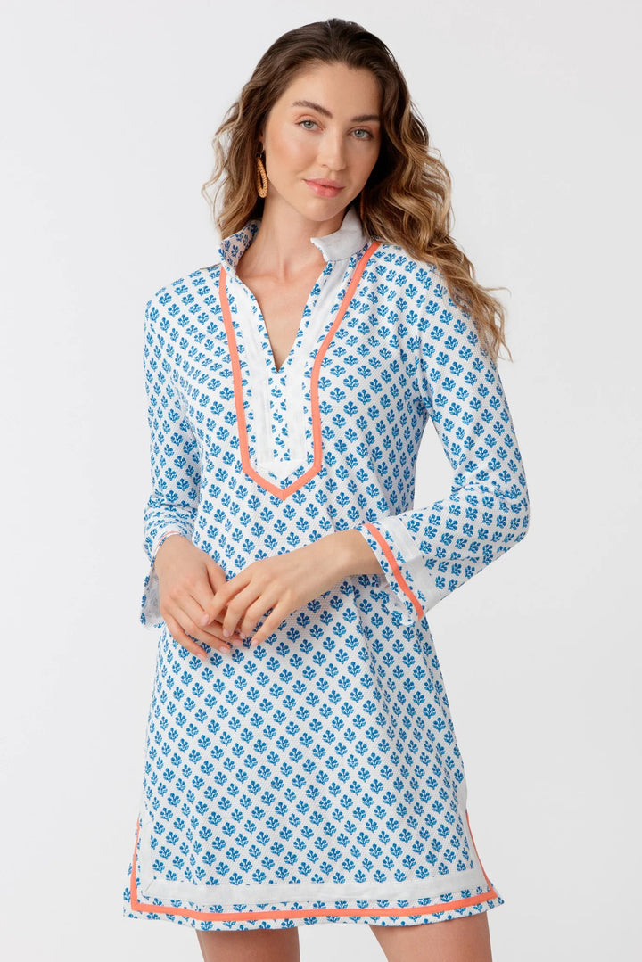 Woman wearing a blue patterned dress with white trim on a light gray background