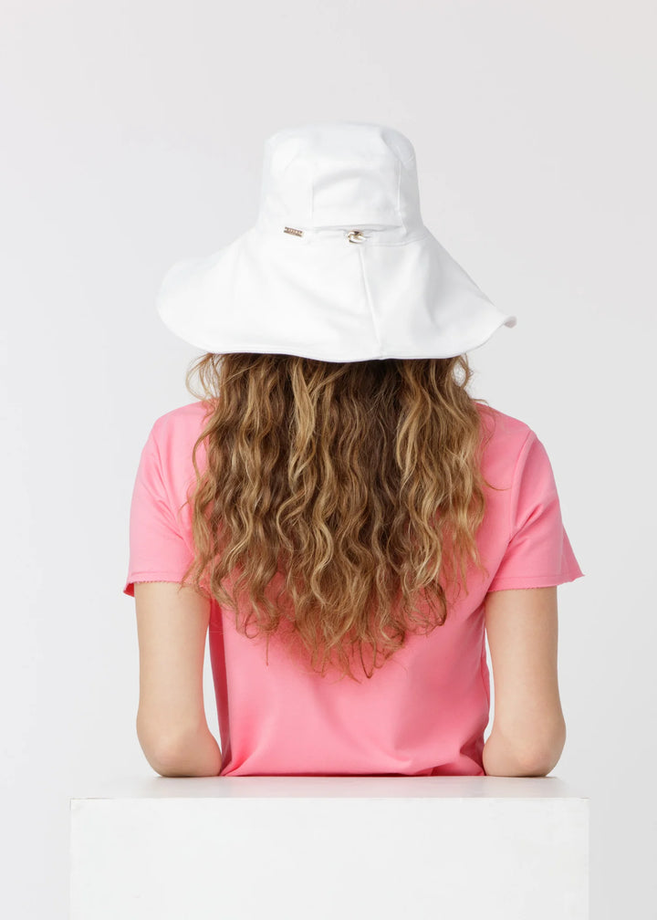 Person wearing a white bucket hat and pink shirt on a light gray background
