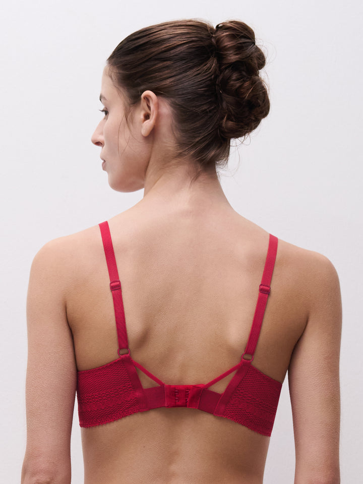 Woman wearing a red bralette against a plain background
