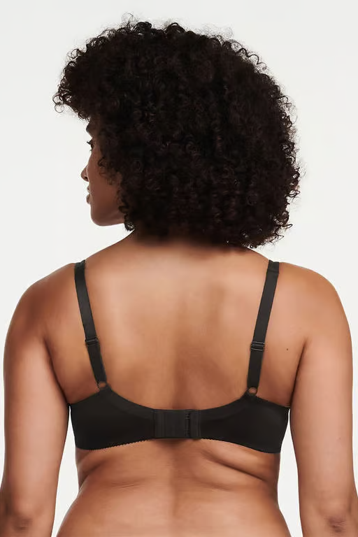 Person wearing a black bra against a neutral background