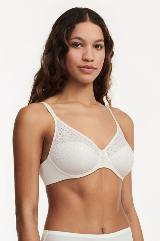 A woman wearing a Chantelle light pink white, molded, underwire bra with floral details and a smooth leotard band. Seamless design with all day comfort and support.