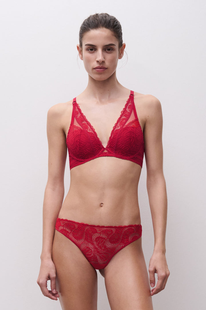 Model wearing a red lace lingerie set against a plain background