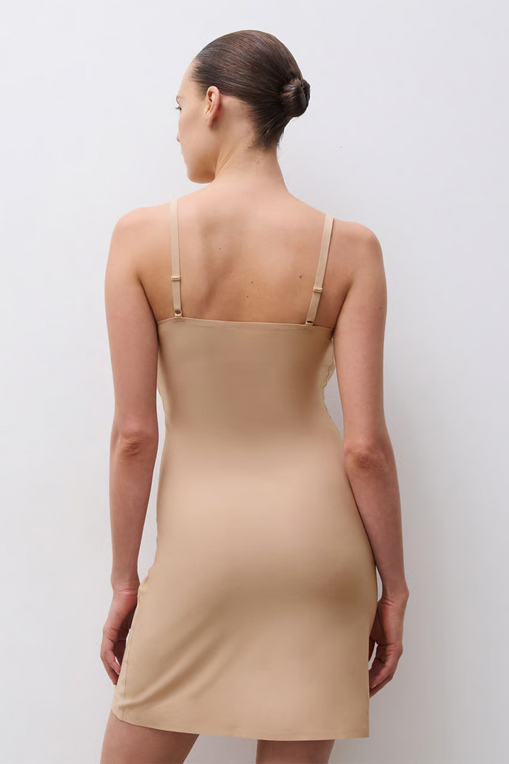 Woman wearing a beige slip dress against a white background