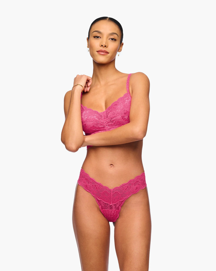 Woman wearing a pink lace lingerie set on a white background