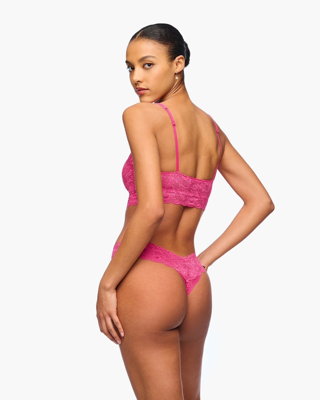 Woman wearing a pink lace lingerie set on a white background