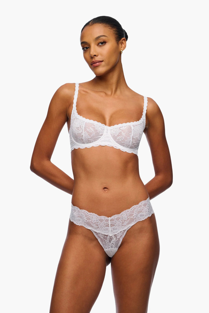 Woman wearing a white lace lingerie set on a plain background