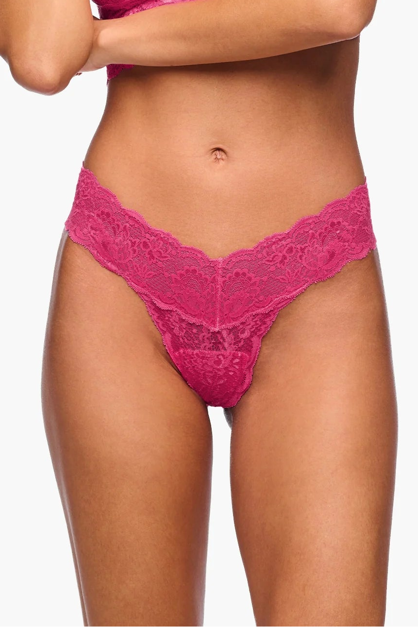 Woman wearing a pink lace lingerie set on a white background