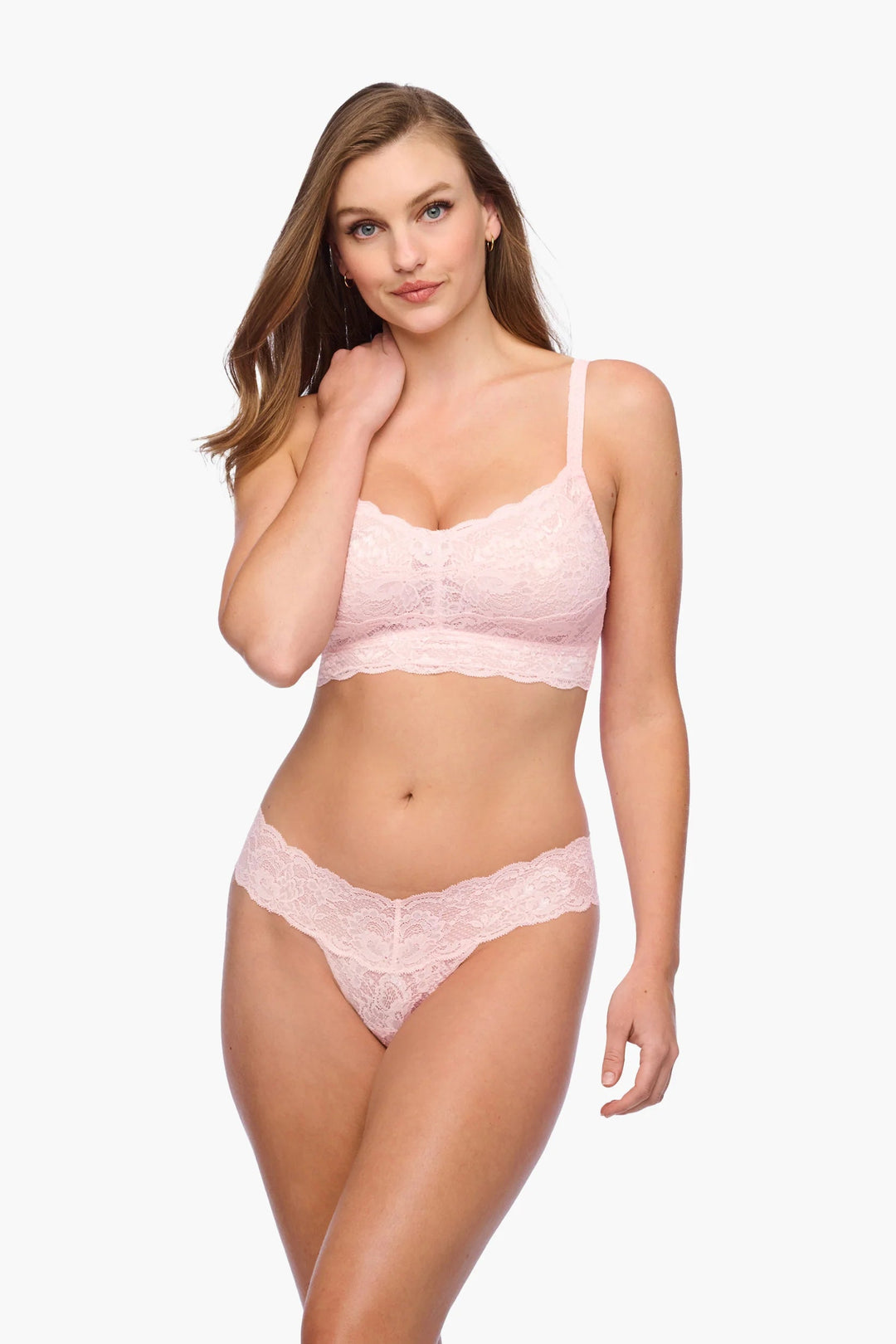 Woman wearing a pink lace lingerie set on a white background