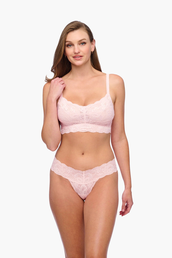 Woman wearing a pink lace lingerie set on a white background
