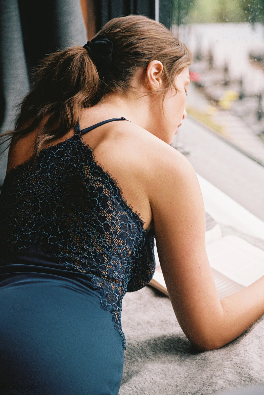 Woman sitting on a windowsill wearing a black lace chemise