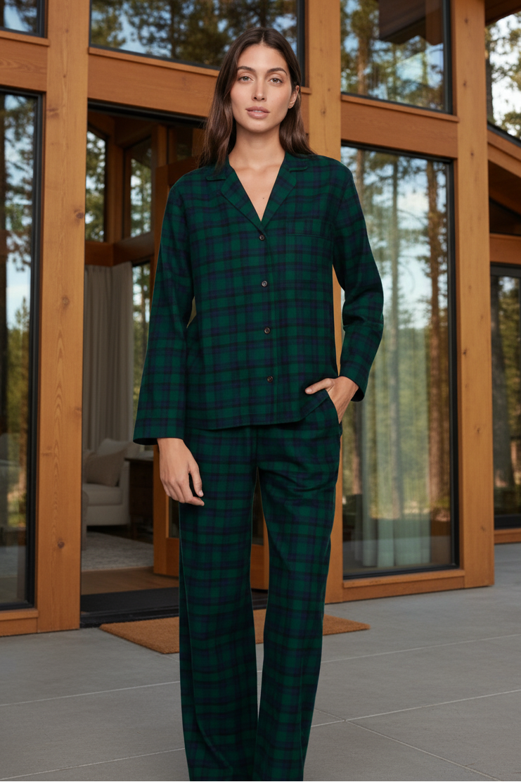 Woman wearing a green plaid pajama set against a cabin
