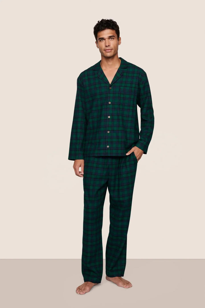 Man wearing green checkered pajamas against a beige background