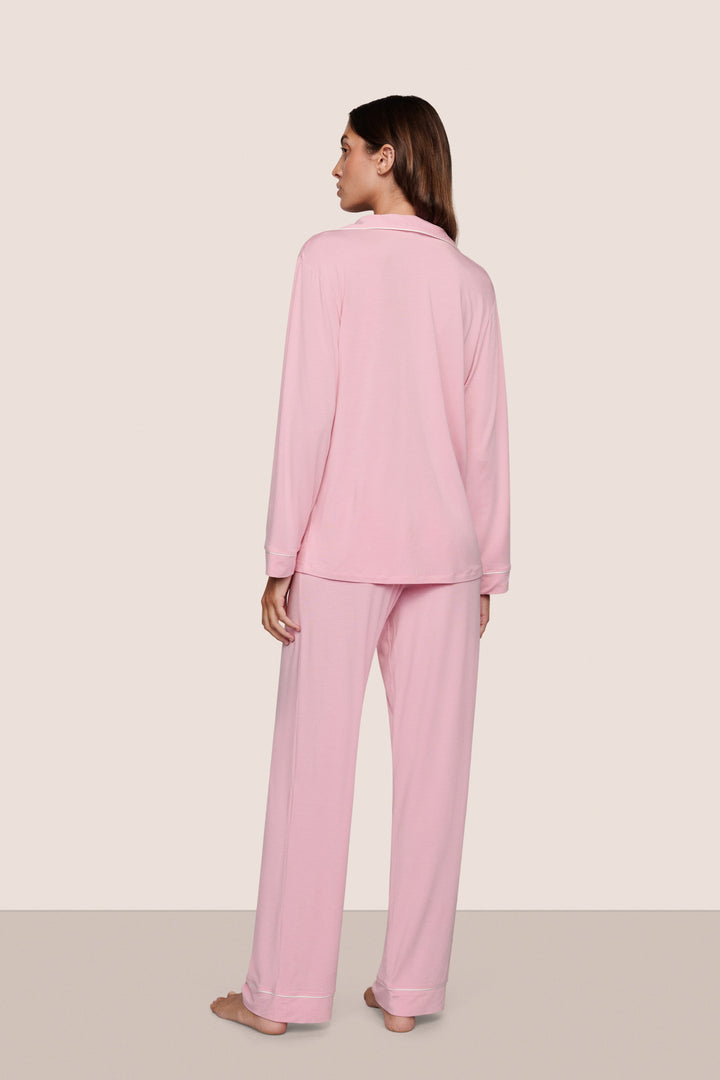 Woman wearing pink pajamas standing against a white background