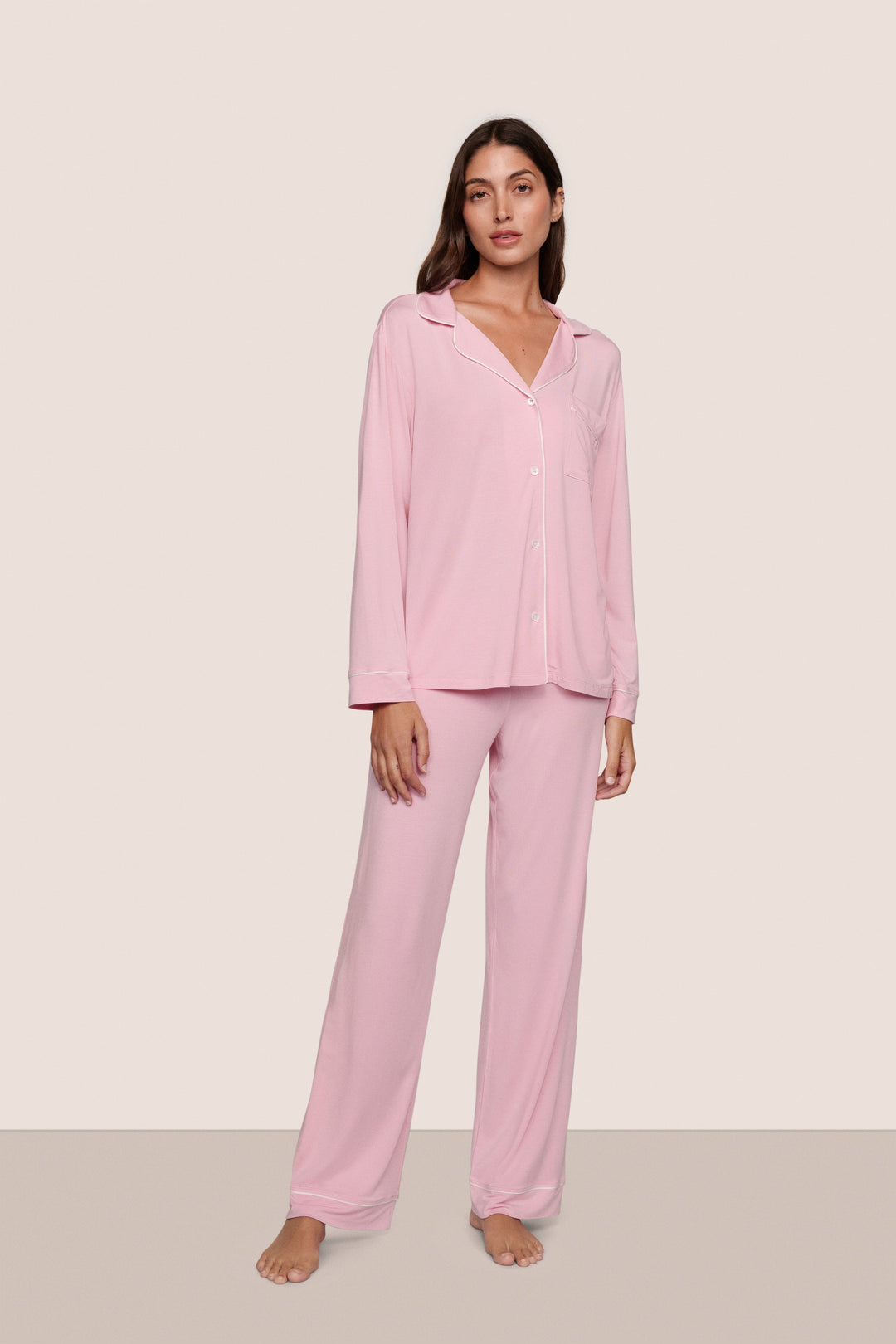 Woman wearing pink pajamas against a plain background
