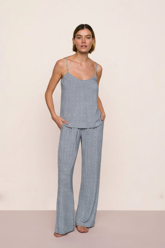 Woman wearing a blue seashell patterned pajama set against a beige background. Great for hot weather and warm sleepers, cool and comfy fabric.