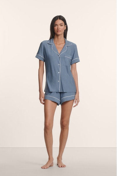 Woman wearing a blue striped pajama set on a plain background