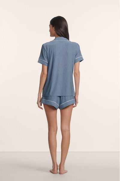 Woman wearing a blue striped pajama set on a beige background