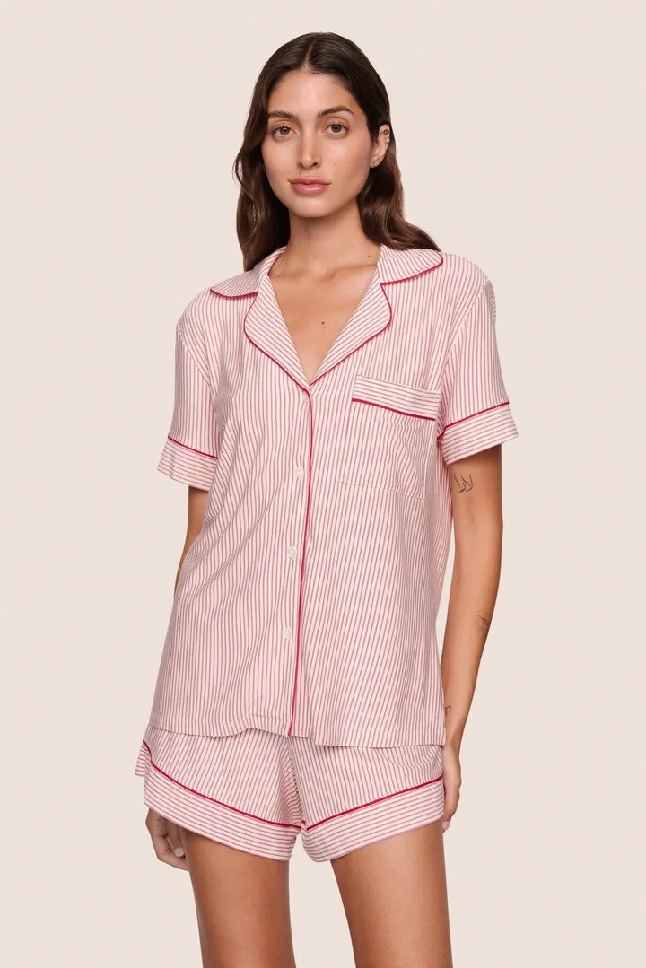 Woman wearing a red and white striped pajama set on a beige background