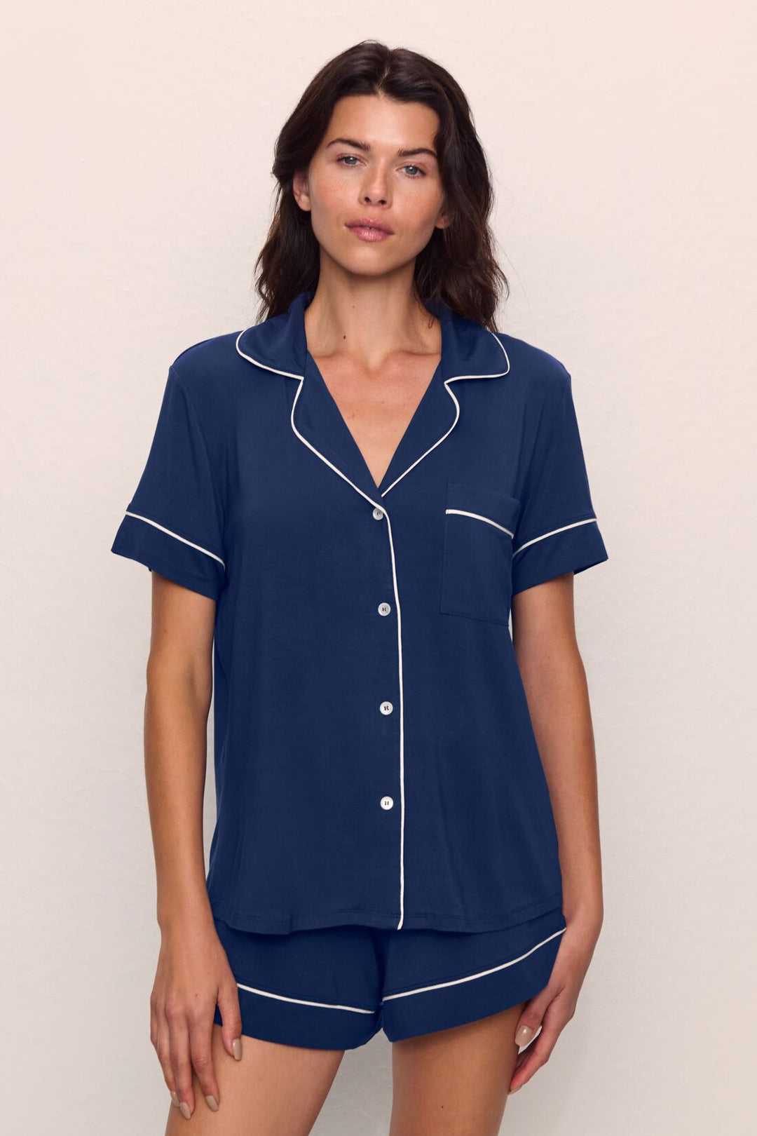 Woman in a navy blue short pajama set with white piping.