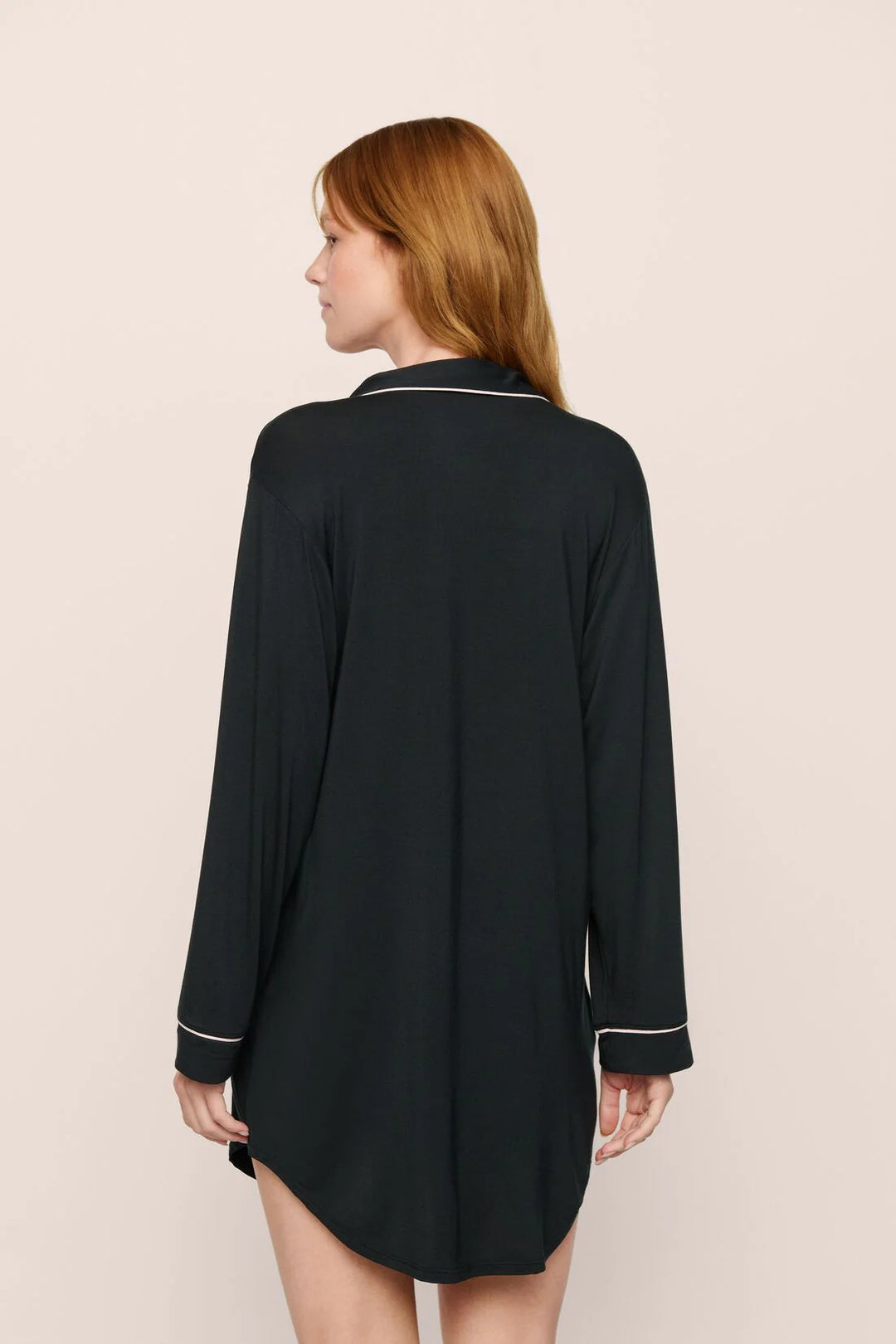 Woman wearing a black nightshirt with white trim on a beige background