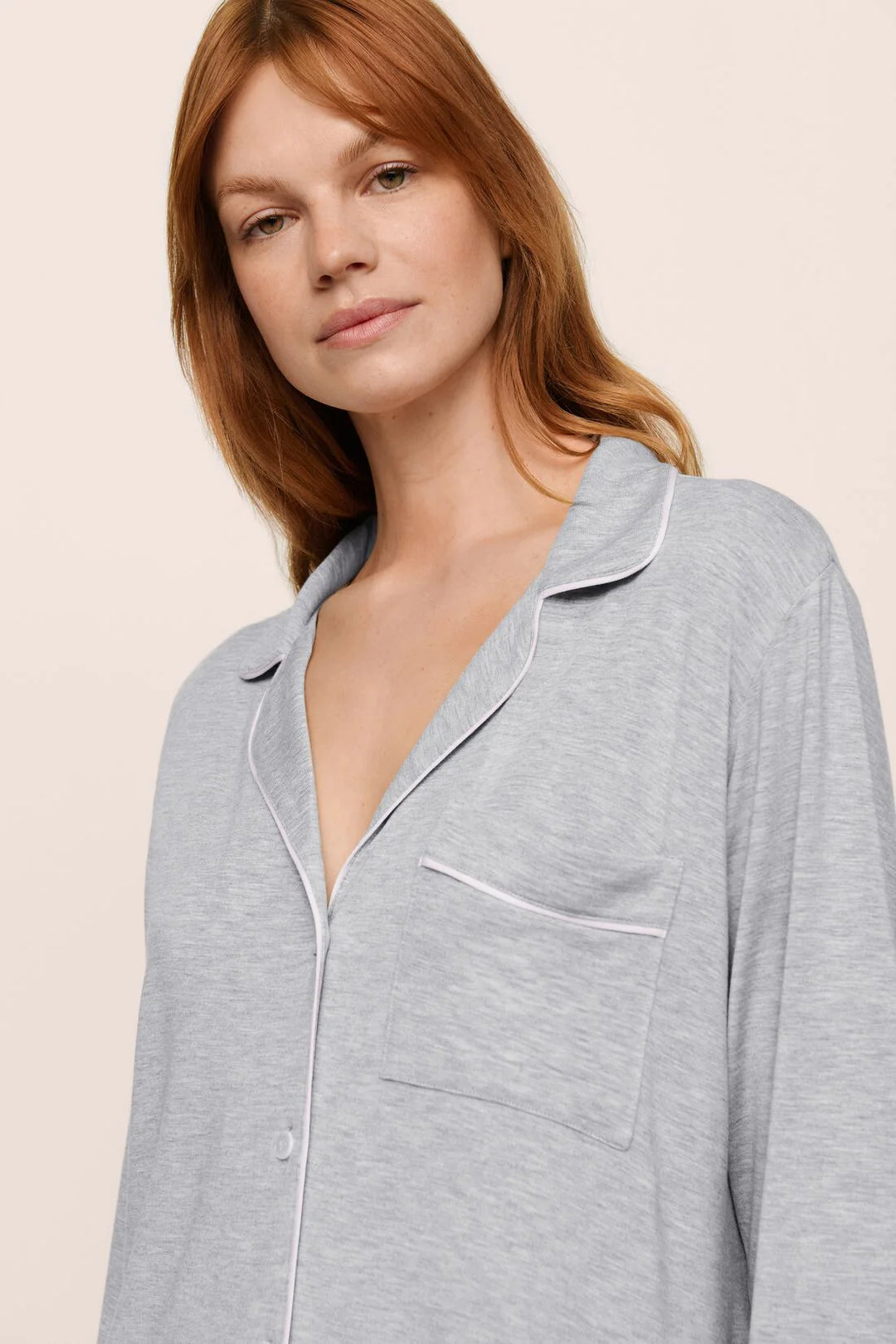 Woman wearing a gray pajama nightshirt against a beige background