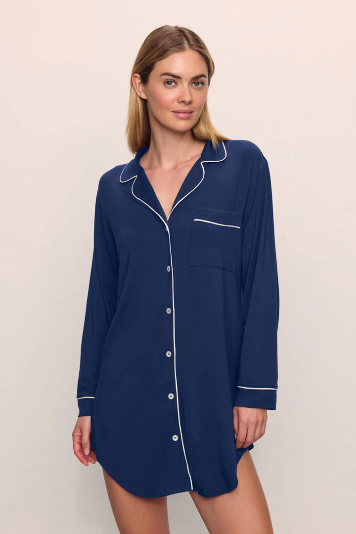 Woman wearing a navy blue nightshirt with white trim on a beige background